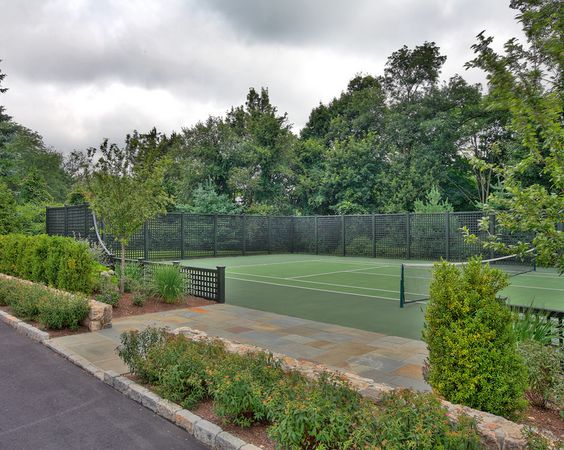 Grön tennisbana omgiven av häckar och grönska